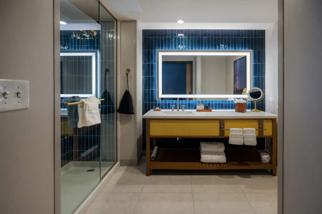 King Standard bathroom with glass shower, deep blue tile, illuminated mirror and wide vanity at Golden Mesa Hotel.